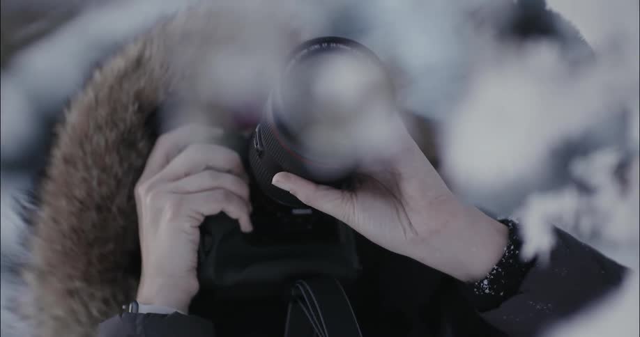 A photographer takes a picture while wearing a heavy coat