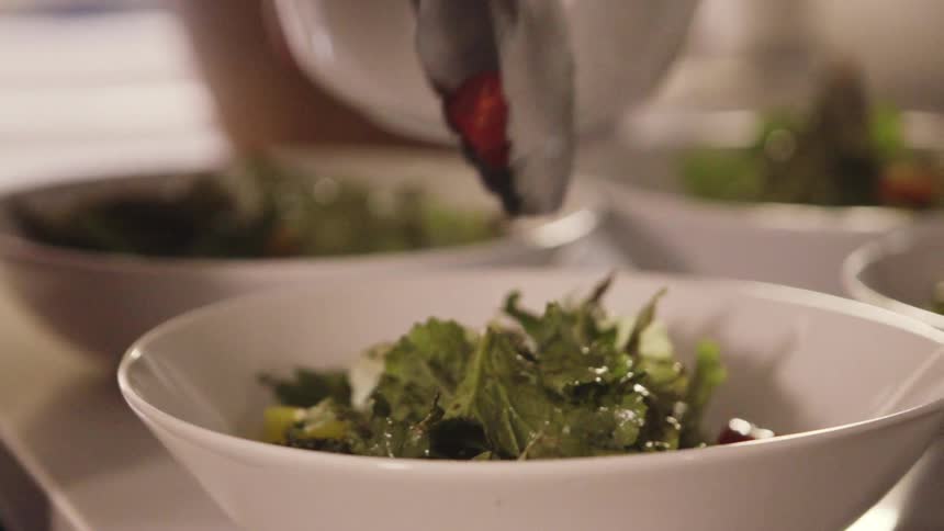 Salad is being put into bowls
