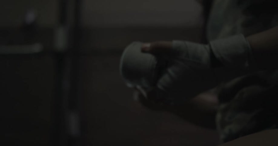 A female fighter picks up a roll of athletic tape and unfurls it