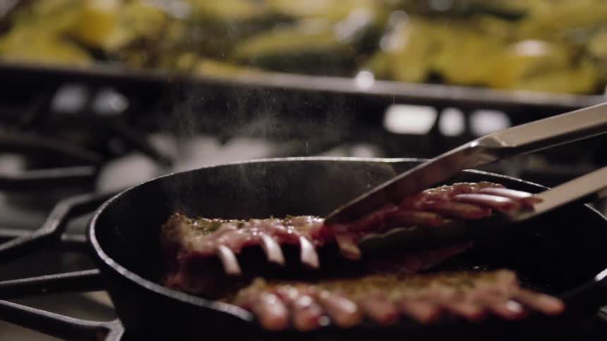 A rack of meat is flipped on a pan