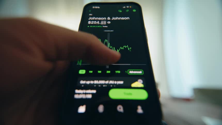 Close-up of a person scrolling through stock market data and analyzing financial charts on a modern investment app on their smartphone