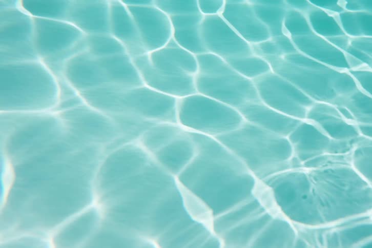 A calming close-up shot of sunlight caustics shimmering on the surface of turquoise water