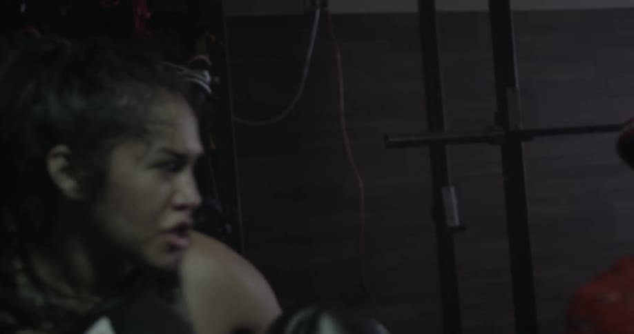A female fighter and her coach are practicing in a gym