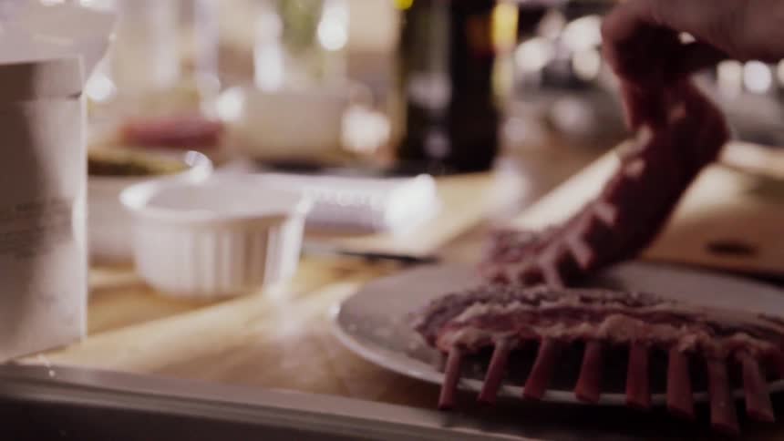 Person reaches into a box of salt and sprinkles it on some meat