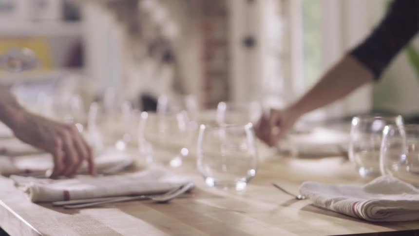 Two people set a dining room table together