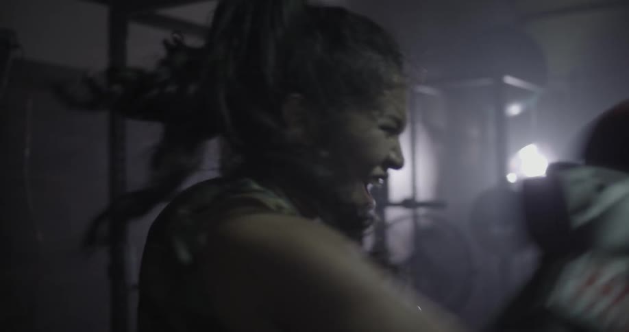A female boxer shouts as she is sparring in a gym