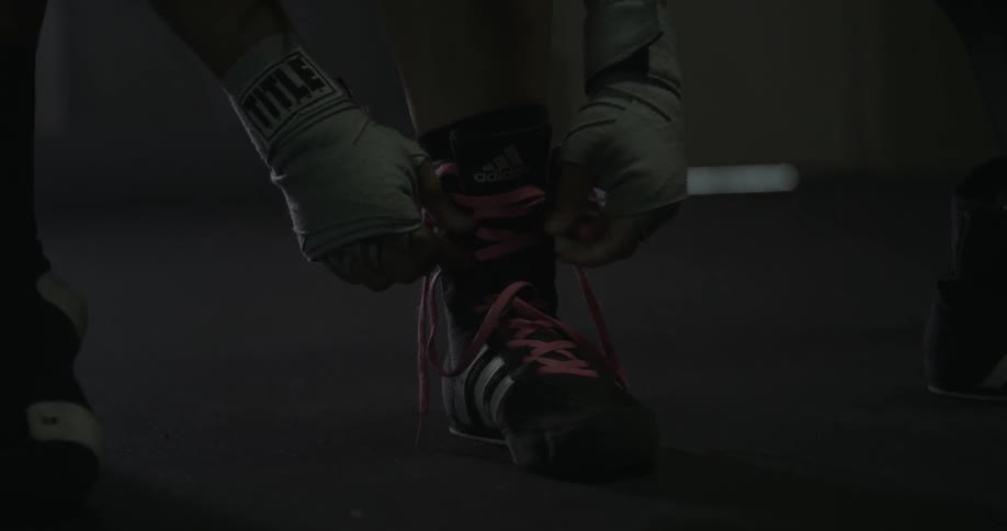 Woman lacing up her shoes with her taped hands