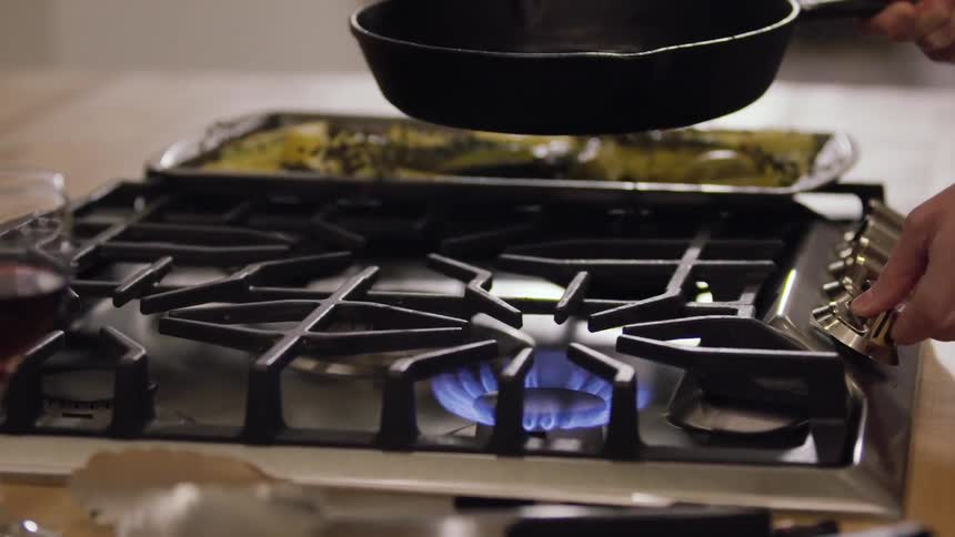 A person puts a pan on the stove to cook