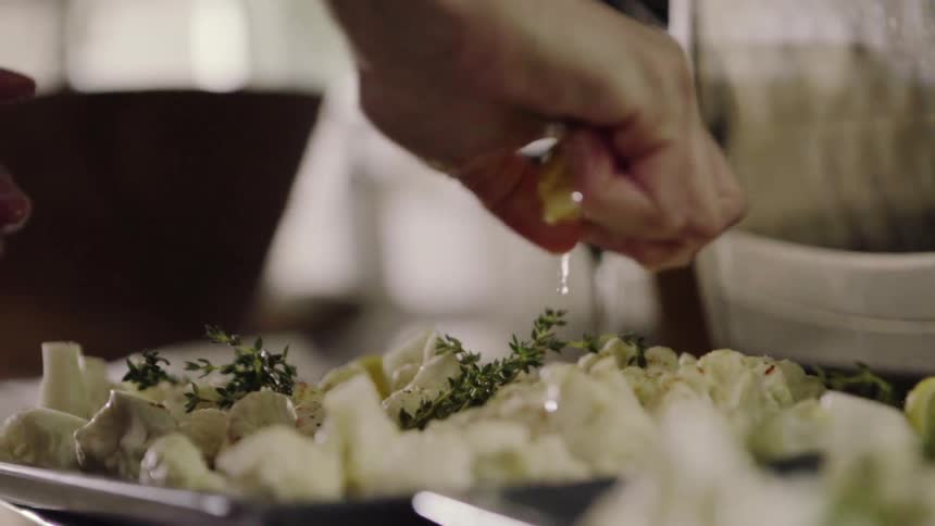 Lemon juice is squeezed onto a plate of cauliflower