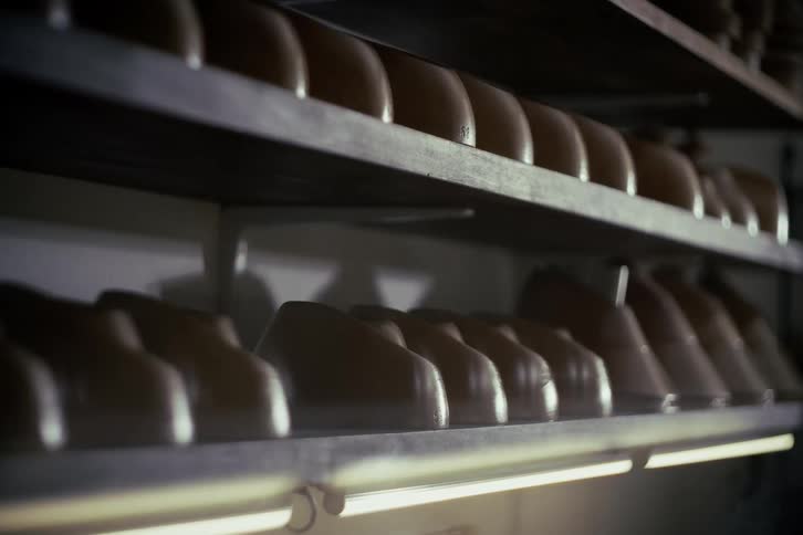 Rows of shoe lasts sit on shelves in a dimly lit shoemaker's workshop