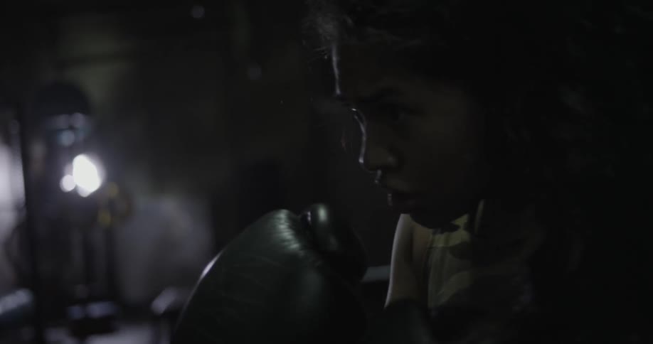 A female fighter is punching a bag in a gym