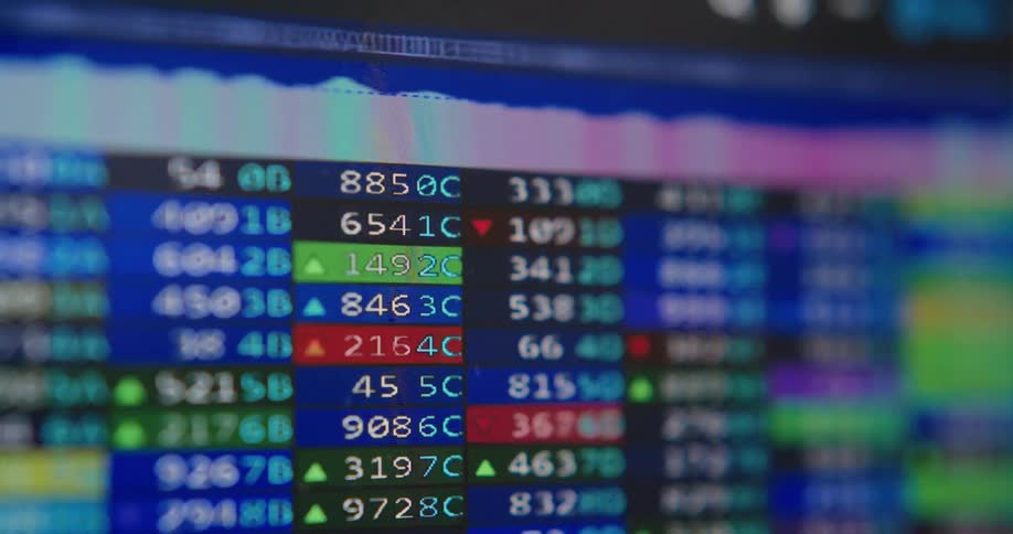A close-up shot of a digital stock market ticker with fluctuating prices and changing colors indicating market trends