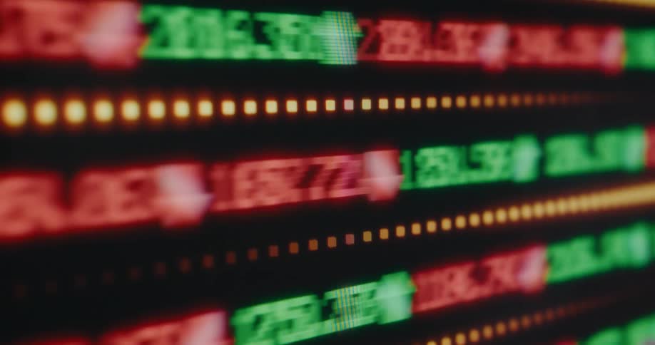 An abstract, out-of-focus digital stock market ticker scrolls rapidly, showing fluctuating financial data in red and green
