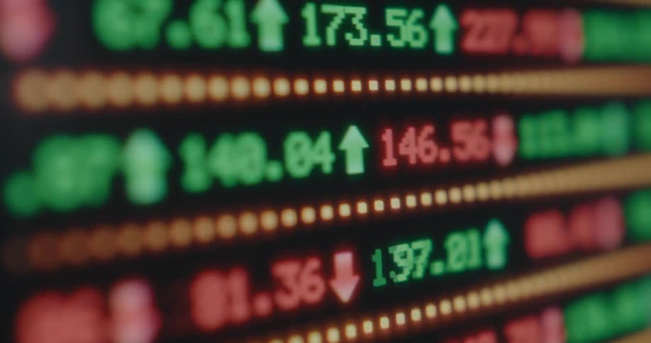 Close-up of a digital stock market board showing real-time price changes, with green numbers rising and red numbers falling