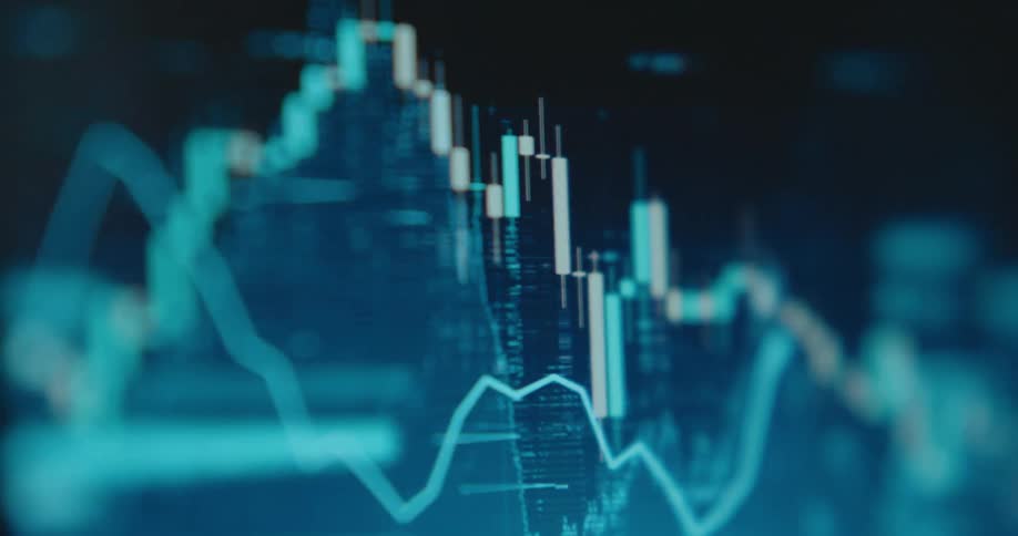 A blurry, close-up view of a digital stock market chart with fluctuating line and candlestick graphs on a screen