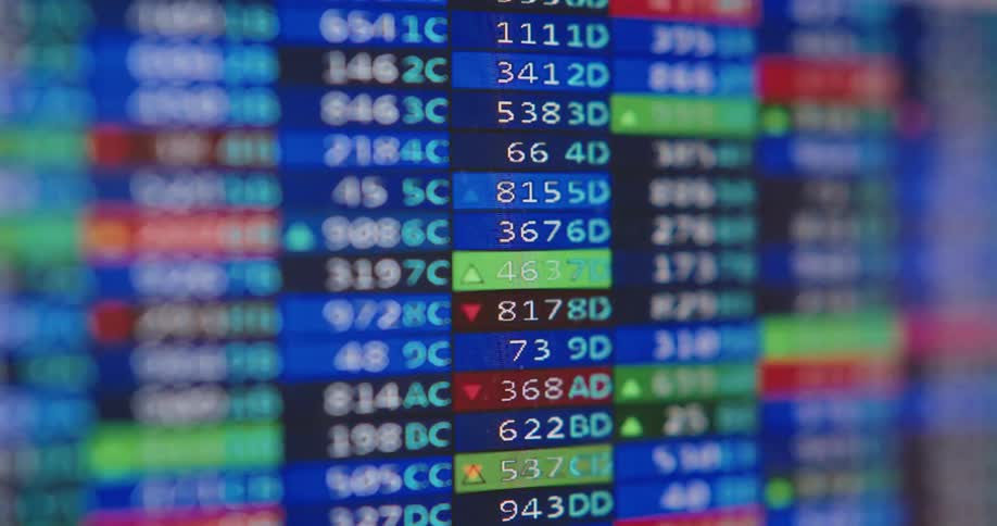 Close up of a flickering digital screen showing a constantly updating stock market ticker with shallow depth of field