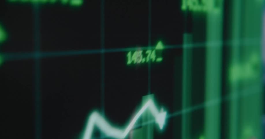 A blurry close-up of a green stock market chart on a digital screen showing fluctuating data and an upward trend