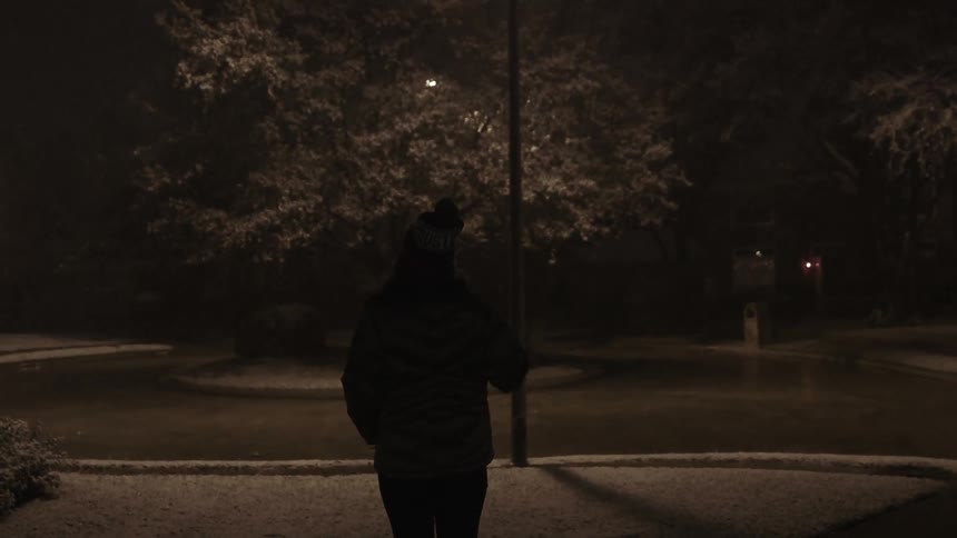 A woman stand outside on a cold and misty night