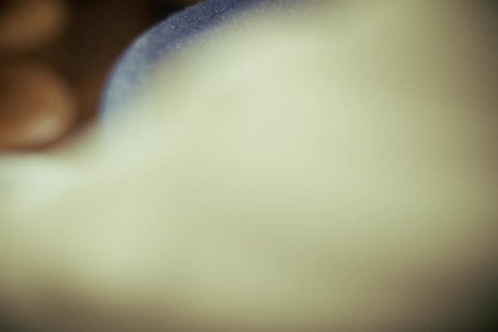 A skilled hatter meticulously pins the sweatband into a dark blue felt hat in a workshop