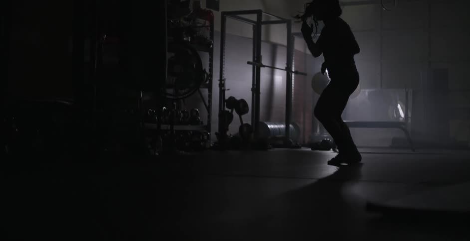 Woman practices boxing moves in a dimly lit gym
