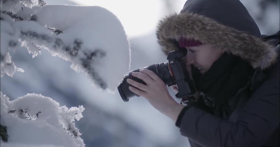 A female photographer is taking a picture in the snow