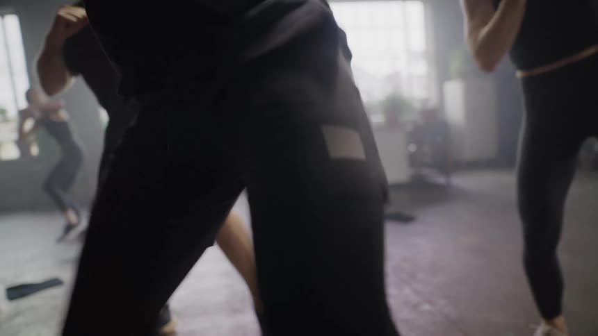 A slow-motion close-up of the legs and lower bodies of a diverse fitness class doing a cardio workout
