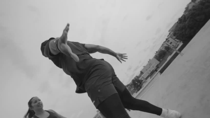 Dynamic slow-motion, black and white footage of two athletes doing agility drills on a rooftop with a rotating camera