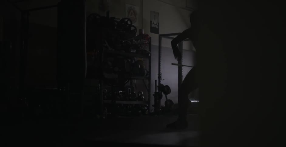 A woman shadow boxes jumping back and forth in front of a lamp