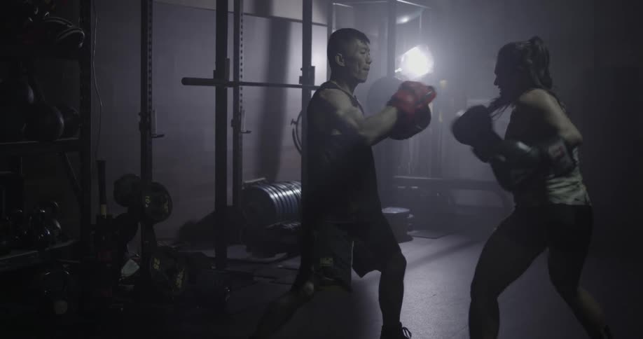 Two people are sparring in a gym