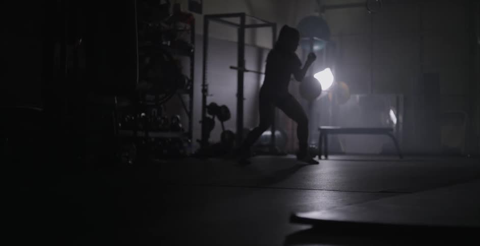 A woman is shadow boxing punching forward in this gym