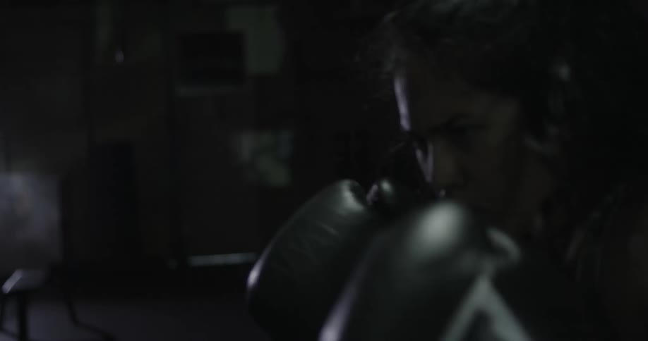 Man and woman practice boxing in a dimly lit gym