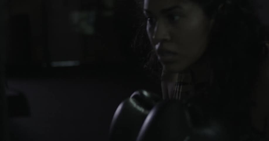 Woman practices punching in a dimly lit room