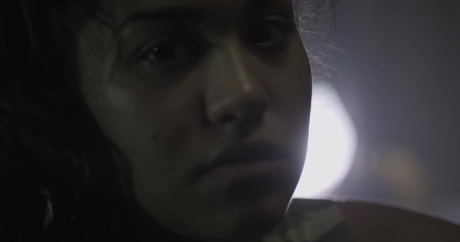 A woman looks around in a dark room