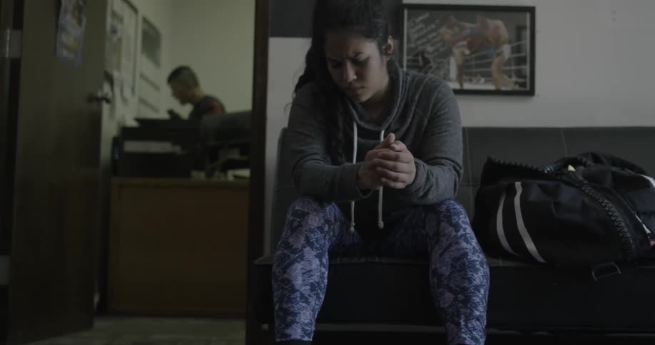 Woman sitting next to her duffel bag indoors