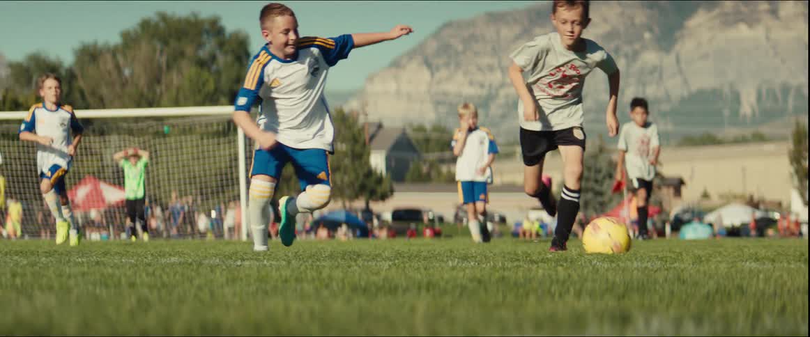 Dynamic slow-motion, low-angle view of a young soccer player skillfully dribbling past a defender during an outdoor match