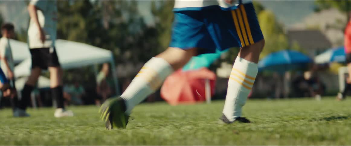 A close-up slow-motion shot of a young soccer player's feet running across a grassy field during a game