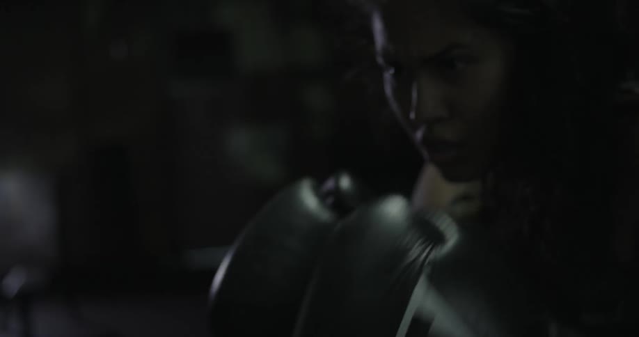 A woman wearing boxing gloves punches a punching bag