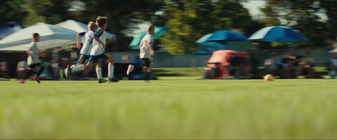 Dynamic slow-motion footage follows a group of young boys running down the field and scoring a goal during a soccer game