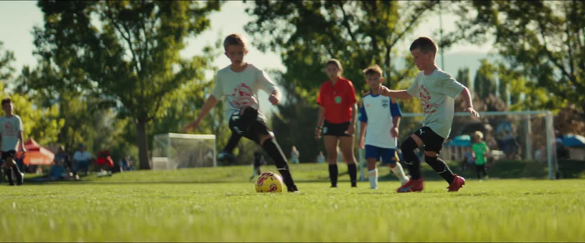 Slow-motion footage follows a team of young boys as they passionately compete in a soccer match on a sunny day
