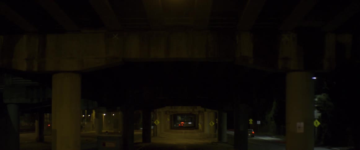 Cars driving under bridge in city at night