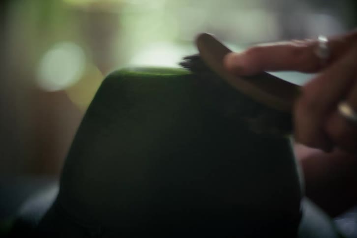 A detailed close-up shot of a person's hand meticulously cleaning a classic green felt hat with a brush
