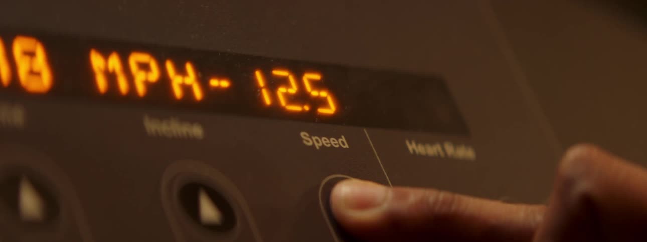 A finger turns up the speed on a treadmill