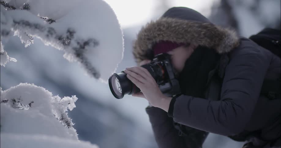 A woman takes photographs outside in the snow