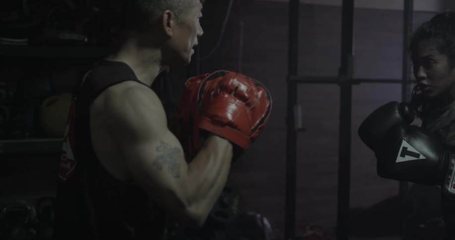Two boxers spar in a dark gym