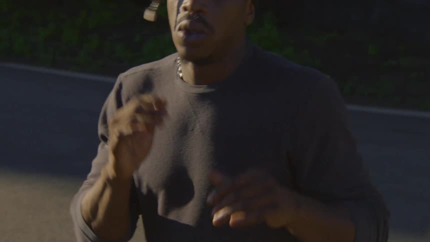 A young Black man in a beanie dances freestyle with intense focus in a dimly lit urban setting