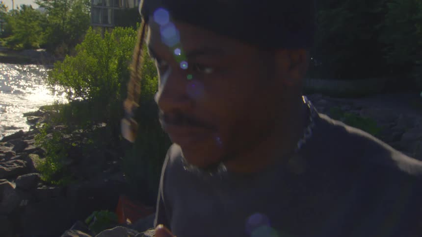Close-up slow motion shot of a man in a beanie enjoying food outdoors by a sunlit lake