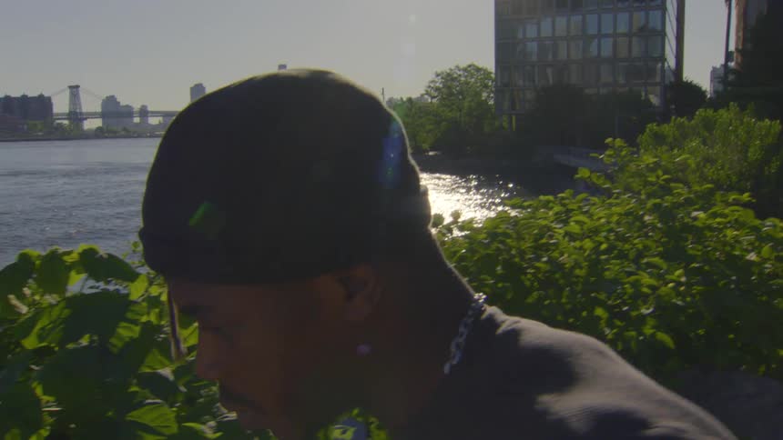 A focused young man jogs along a city riverfront in slow motion with the bright morning sun flaring behind him
