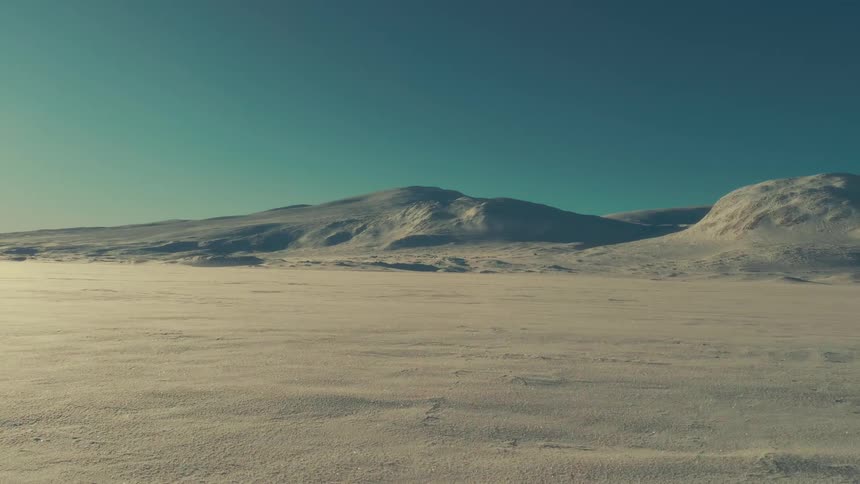 A ground blizzard sweeps across a desolate, sunlit snowy landscape under a clear teal sky