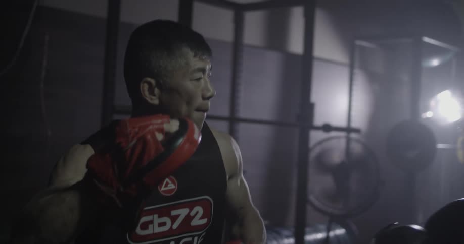 Man and woman in dark gym practicing boxing