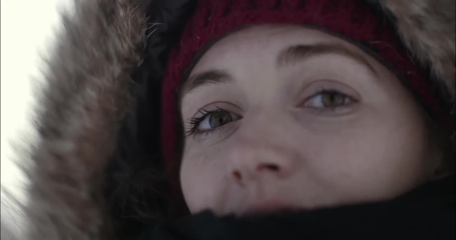 A woman is a fur-lined parka is staring